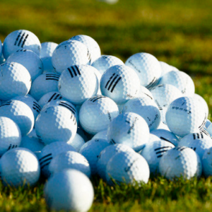 Pile of white golf balls stacked on grass – golf clinics for beginners