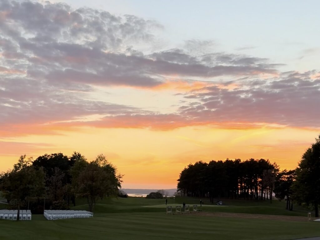 Sunset over River Oaks Golf Course with colorful sky, tree-lined fairway, and event setup in Cottage Grove Minnesota