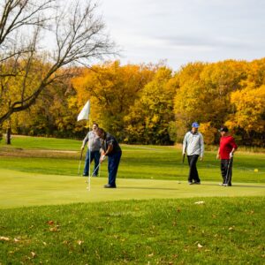 Golfers putting on a green surrounded by fall colors at River Oaks Golf Course in Cottage Grove Minnesota