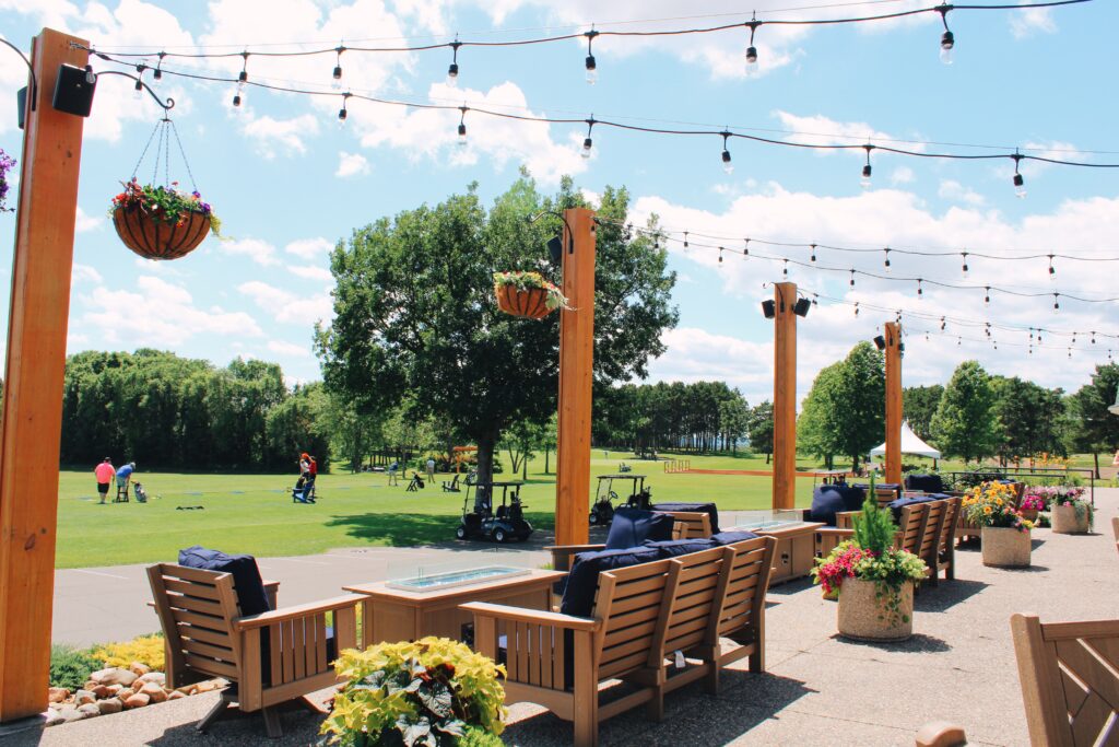Outdoor patio seating overlooking the driving range at River Oaks Golf Course and Event Center in Cottage Grove Minnesota
