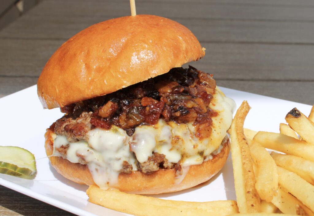 Bacon Pepper Jam Burger from Eagles Bar & Grill featuring a double smash burger topped with melted pepper jack cheese, house-made bacon pepper jam, and served with fries.