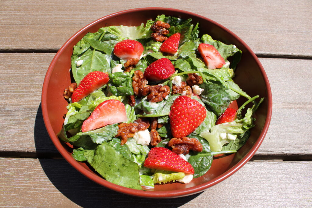 Summer Strawberry Salad from Eagles Bar & Grill featuring fresh strawberries, mixed greens, feta cheese, candied walnuts, and poppyseed dressing.